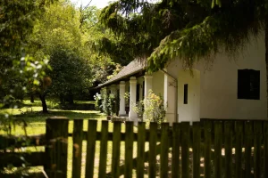 Rustic white house with a columned porch and wooden fence